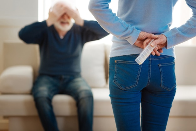 Raad maar. Blije gepensioneerde die positiviteit uitdrukt en de ogen bedekt terwijl hij op de bank zit