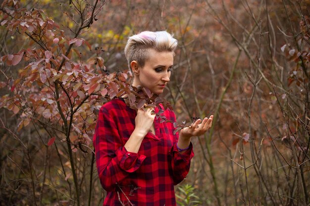 Foto raadselachtige mysterieuze vrouw met kort haar op herfstbosachtergrond met verdorde struiken