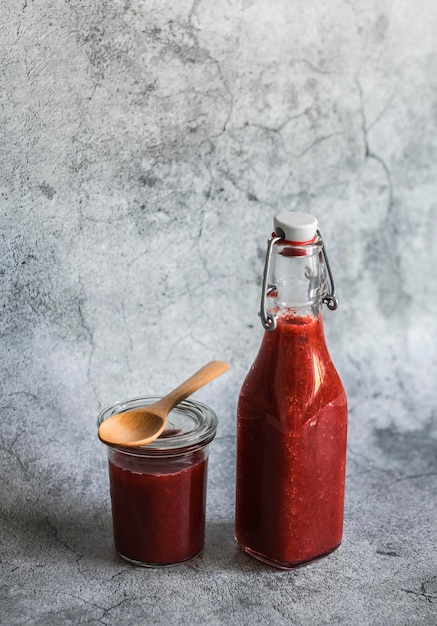 Rabarber en aardbei zoete saus in een ingeblikte fles op een grijze achtergrond Vrije ruimte voor tekst