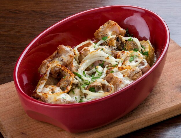 Rabbit baked in sour cream with onion in ceramic bowl