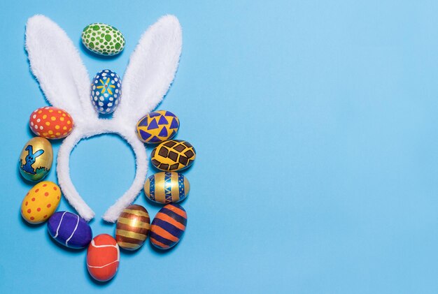 Rabbit ears and Easter eggs on a blue background, space for text