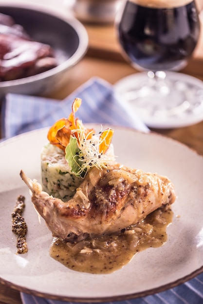 Rabbit leg with mashes potatoes and decoration on plate in restaurant.