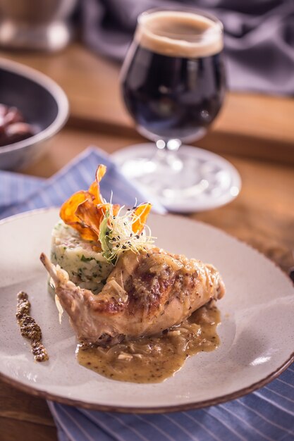 Rabbit leg with mashes potatoes and decoration on plate in restaurant.