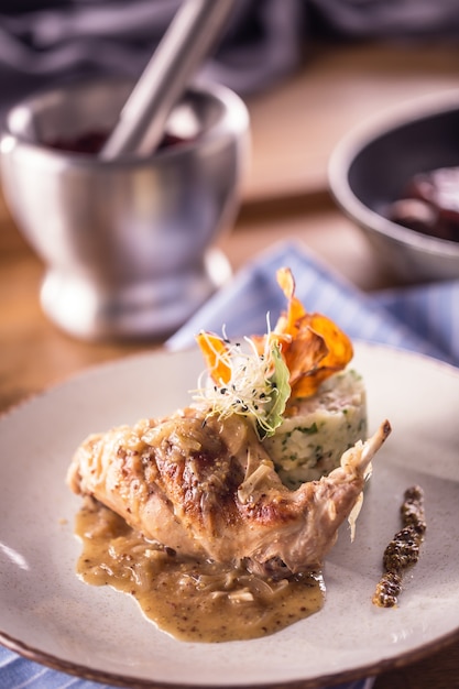 Rabbit leg with mashes potatoes and decoration on plate in restaurant.