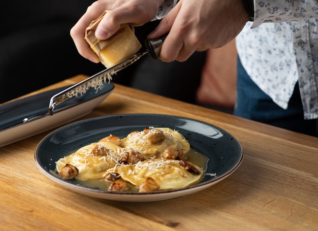 Rabbit ravioli with mushroom sauce and its rapeseed parmesan cheese on the table at restaurant