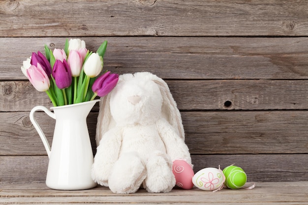 Rabbit toy easter eggs and colorful tulips