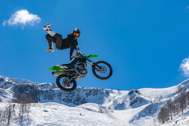 Racer on a motorcycle in flight in snowy mountains