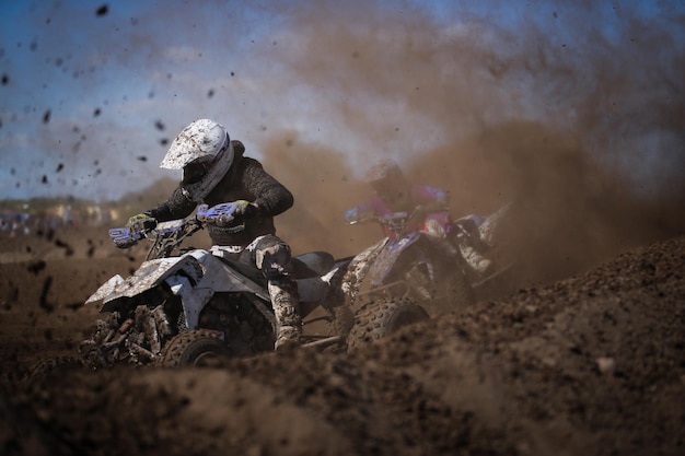 Racers riding quadbike in dirt during race