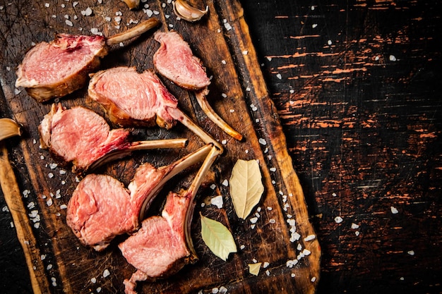 Rack grilled lamb on a cutting board with bay leaves