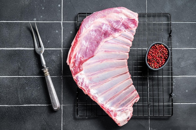 Rack of lamb raw mutton ribs on kitchen table with spices Black background Top view