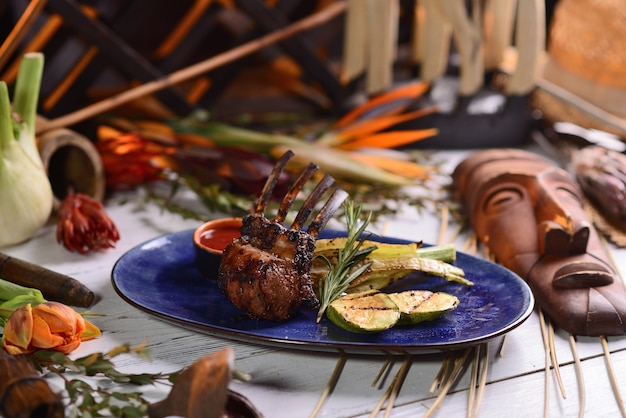 Rack of lamb with baked vegetables and sauce. In the blue plate