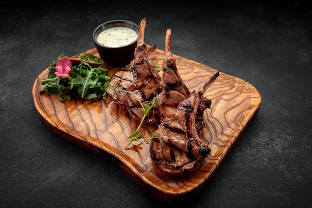 Rack of lamb with sauce and herbs on a wooden board