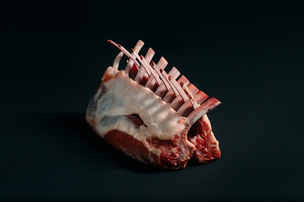 A rack of new Zealand Lamb in raw form on black.