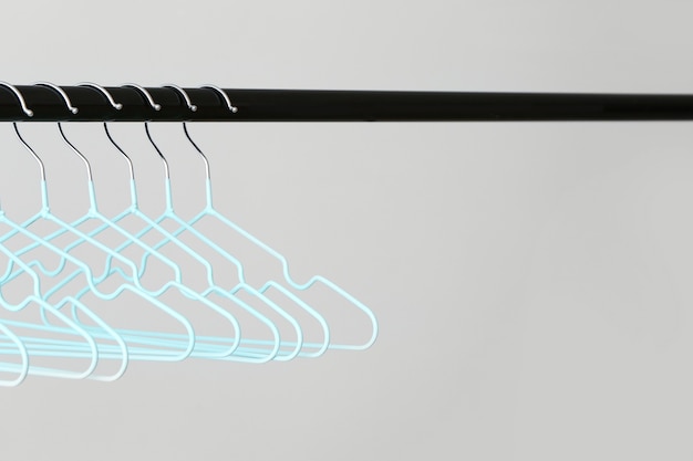 Rack with clothes hangers on light background