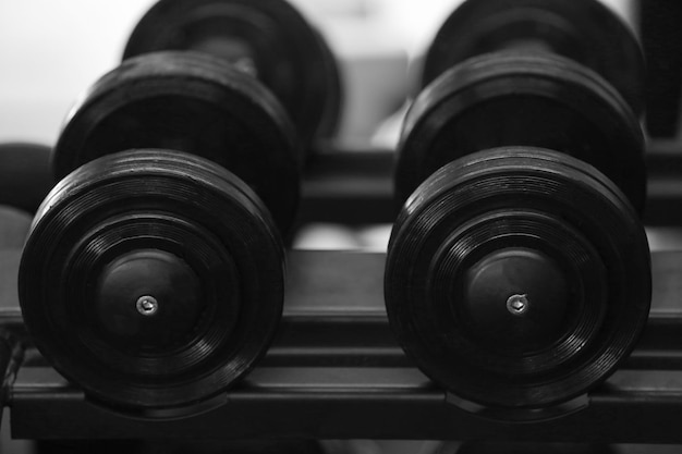 Rack with different dumbbells in gym close up