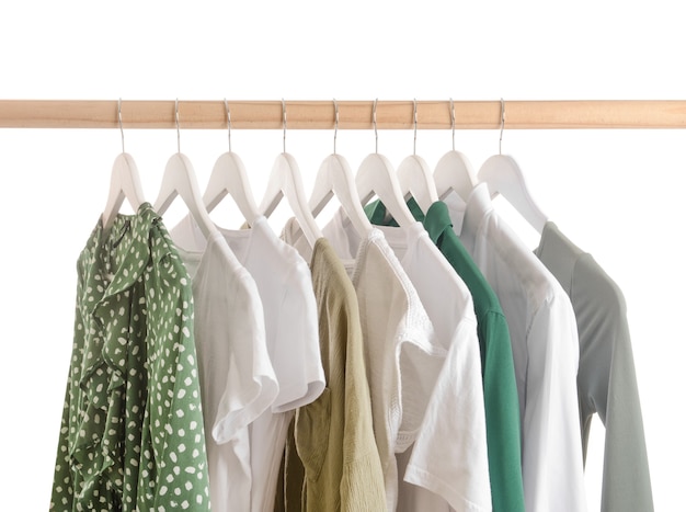 Rack with hanging clothes on white wall