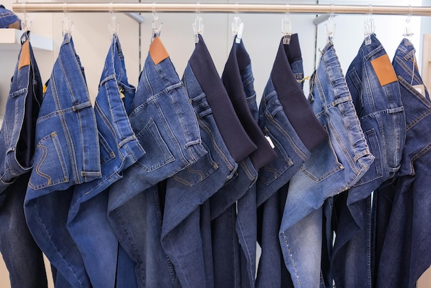 Rack with stylish jeans near brick wall closeup