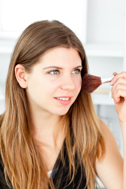 Radiant woman using a powder brush in her bathroom