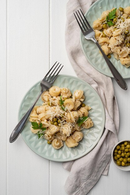 Photo radiatori pasta with bechamel sauce with green peas cheese and parsley in mint colored plate on wooden background