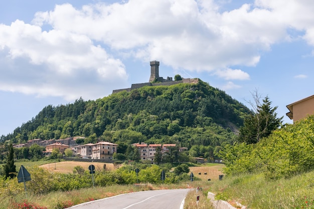 아래 Radicofani 마을과 현무암 절벽에 Fortezza di Radicofani 요새 이탈리아 투스카니