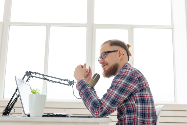 Radio, DJ, blogging and people concept - Smiling man sitting in front of microphone, host at radio