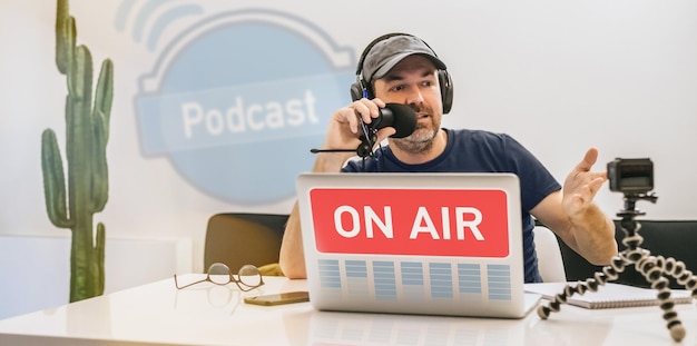 Photo radio host in headphones recording podcast in studio man streaming audio using microphone and laptop