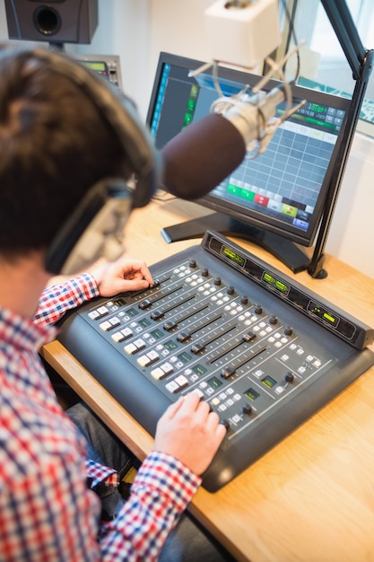 Photo radio host using sound mixer on table