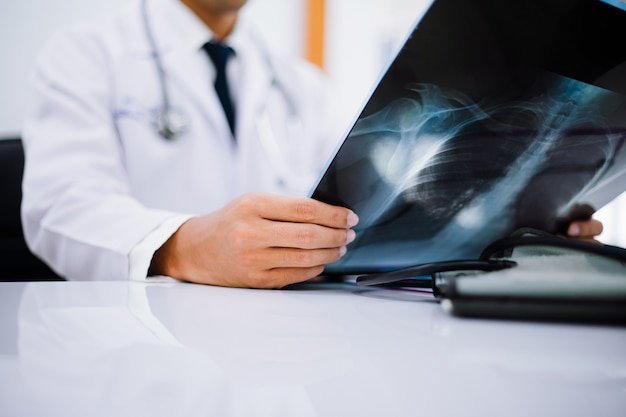 Radiologie arts die bij borst x ray film van patiënt bij gezondheidszorgkliniek onderzoekt