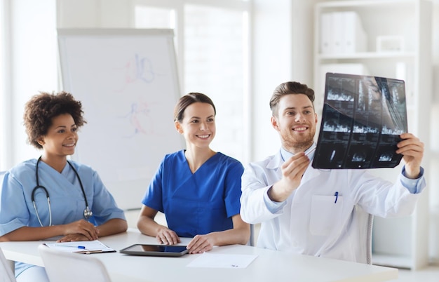 Radiologie, mensen en geneeskundeconcept - groep gelukkige artsen die röntgenfoto's bekijken en bespreken in het ziekenhuis