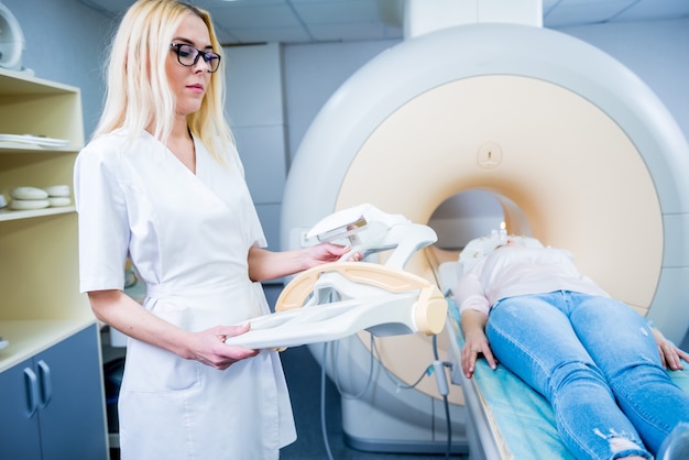 Radiologist prepares young woman for an MRI brain examination.