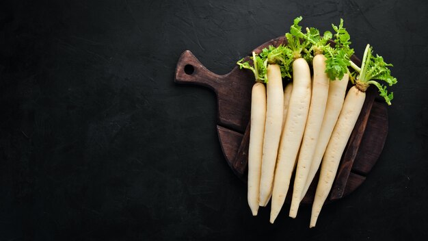 Foto ravanello daikon su sfondo nero ravanello verdure vista dall'alto spazio libero per il testo