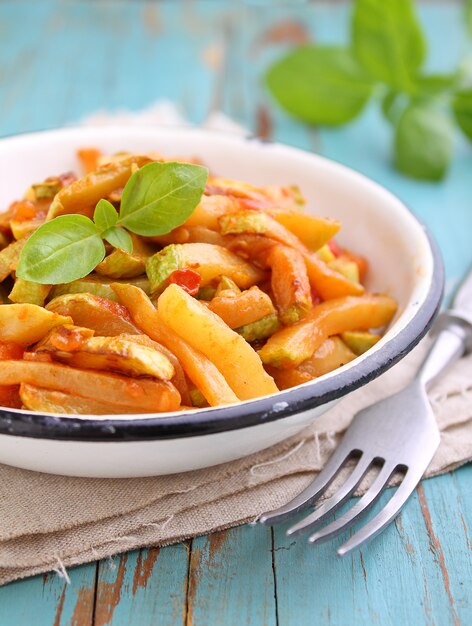 Ragout van courgette en tomaat met knoflook en basilicum, in een witte plaat, selectieve aandacht