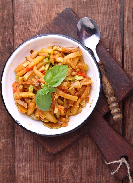 Ragout van courgette en tomaat met knoflook en basilicum, in een witte plaat, selectieve aandacht