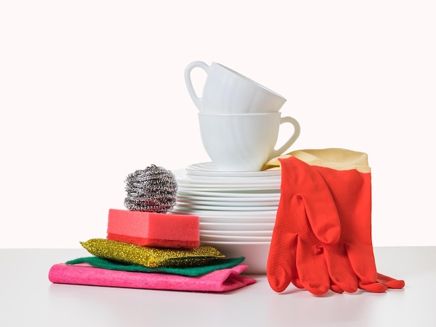 Фото Тряпичные губки, перчатки и набор посуды на белом столе