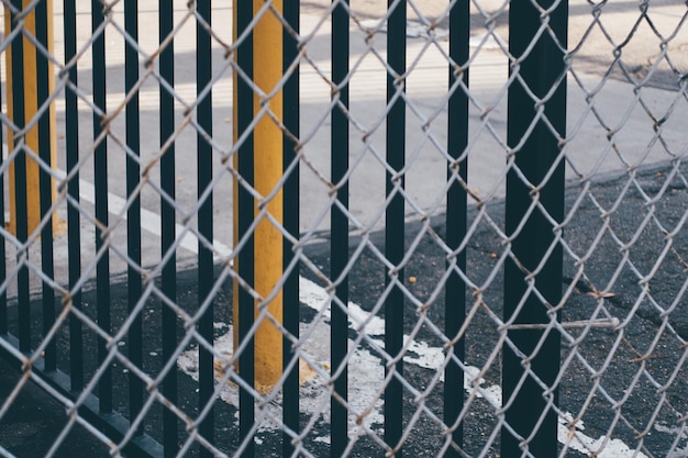 写真 チェーンリンクのフェンスを通って見られる歩道のレール