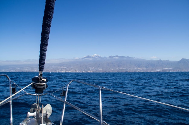 Railing van een schip op zee met een berg op de achtergrond