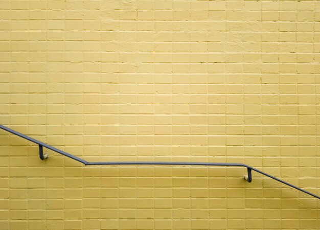 Railings of gray metal near a yellow brick wall. Yellow background, brick texture. Minimalism. Copy space