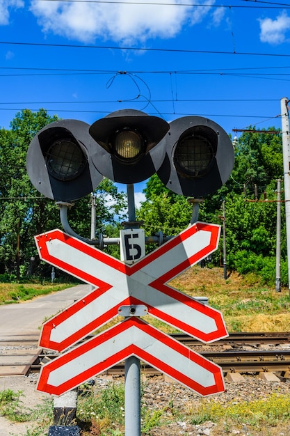 Photo railroad crossing sign and semaphore in front of the railroad crossing