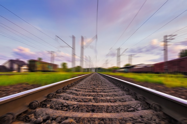 Railroad in motion with motion blur effect at sunset with beautiful sky and purple clouds. 