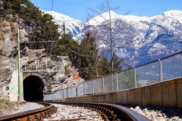 写真 雪で覆われた山々を横断するトンネルに向かう鉄道線路