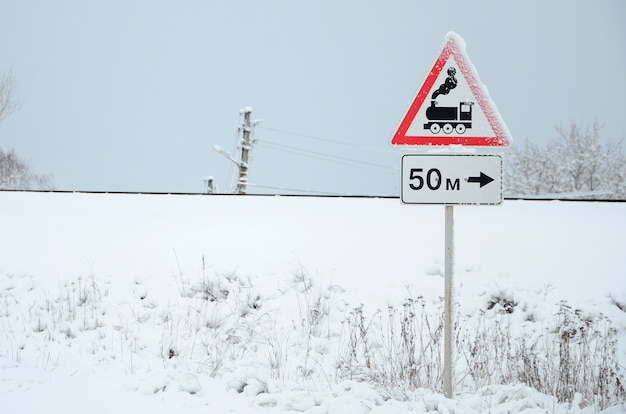 Railway crossing without barrier. A road sign depicting an old black locomotive, located in a red triangle