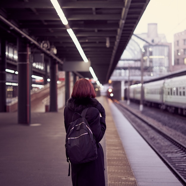 鉄道駅。美しい少女はプラットフォームに立って、電車を待っています