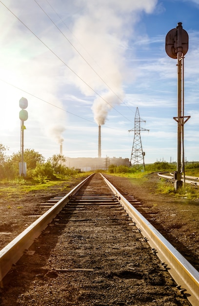 Railway track with traffic light on the background of factory pipes  Vorkuta Russia