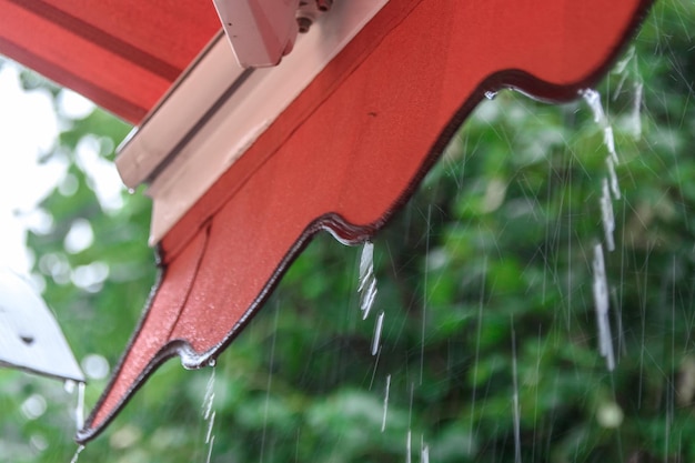 Rain drips down from the roof of a summer cafe