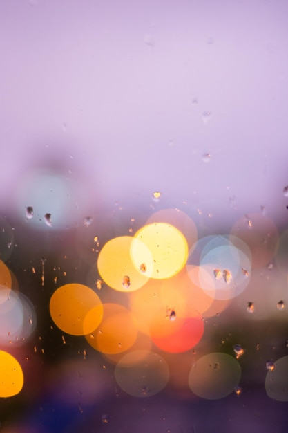 Rain drops in blue glass background City street lights bokeh defocused abstract dusk night city background