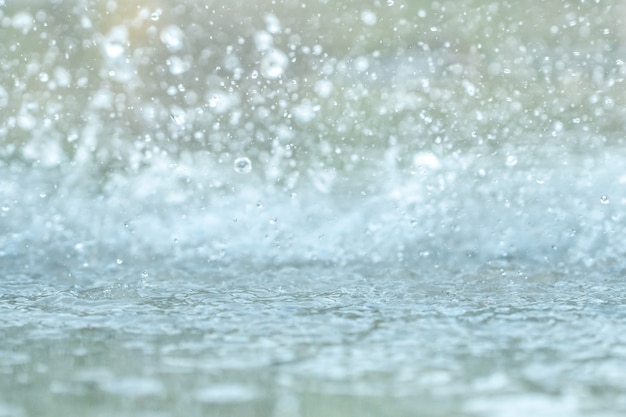 町のアスファルトの上に大きな水たまりに降る雨の滴。