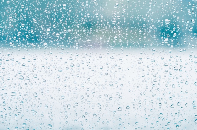 Rain drops and frozen water on window glass background, blue toning