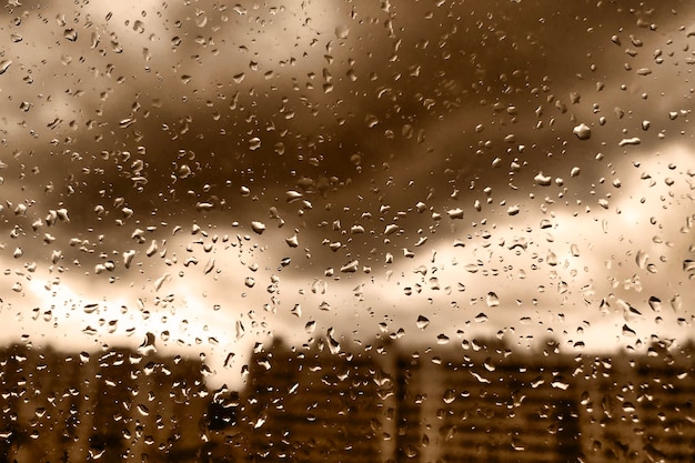 オレンジ色の背景のガラスに雨の滴