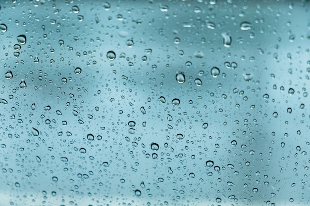 Капли дождя, вода падает на стекло весной. абстрактный фон