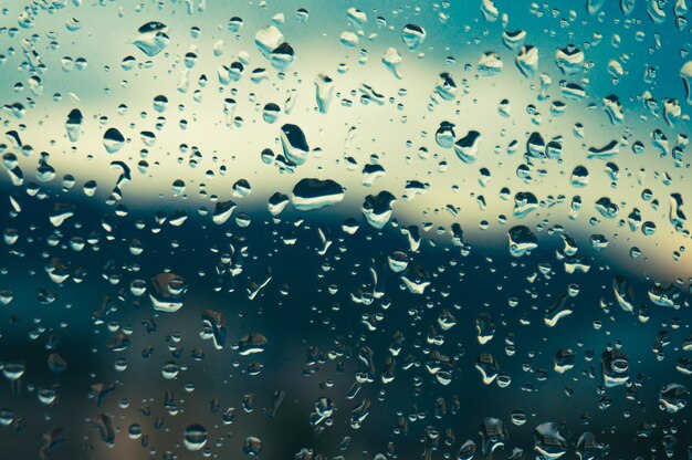 Rain drops on window glasses surface with sunset drops on glass spray on window background for dark text view selective focus